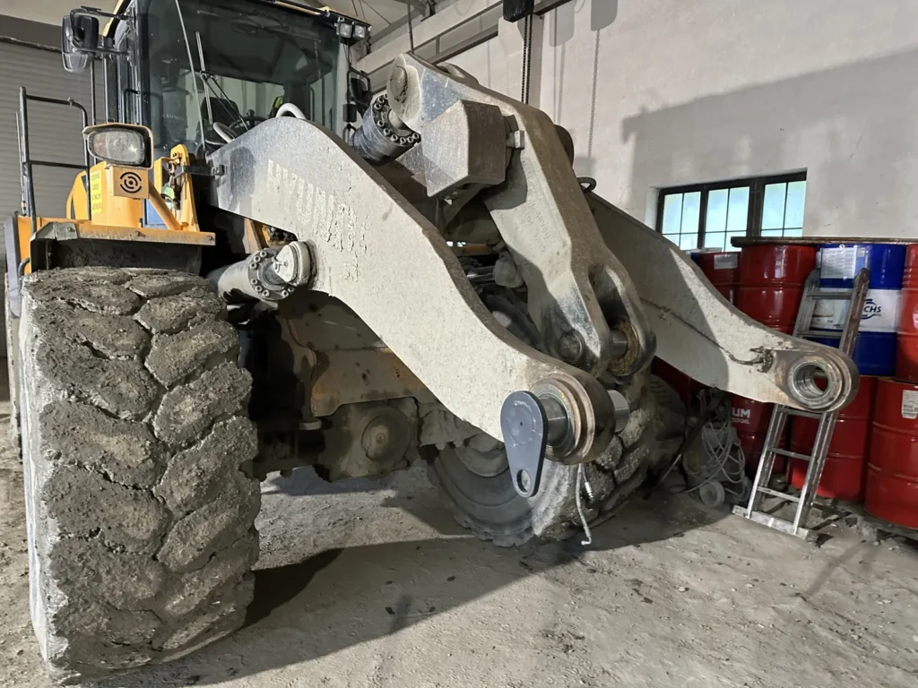 Zbliżenie ramienia ładowarki Hyundai z zamontowanymi sworzniami i tulejami w uchach mocowania